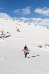 Woman in knitted cardigan running at virgin snow field high in mountains. Happy emotions