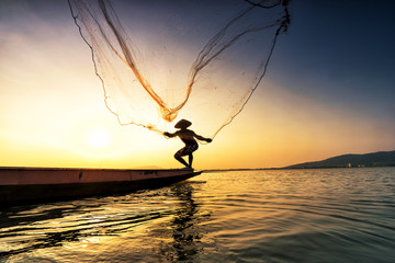 Fisherman on a fishing boat in a river at sunset,Thailand