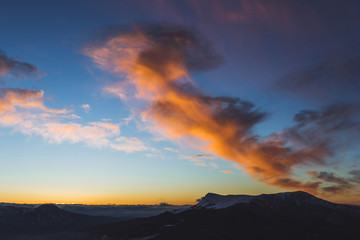 Amazing colorful sunset high in mountains. Orange clouds and blue sky