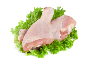 Two raw chicken drumsticks with lettuce leaf isolated on white background