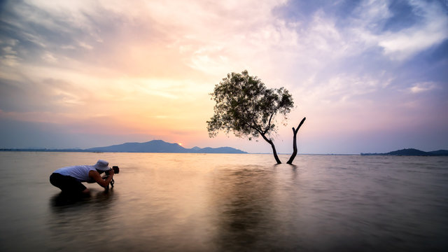 Asia a man nature photographer,Photographer is taking a picture of sunrise at beach with beautiful sky reflections