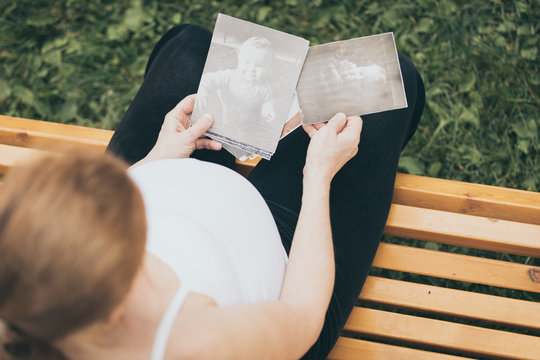 pregnant woman sitting on the bench and looking сhildren's photos