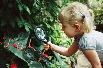 Portrait of cute adorable white Caucasian girl looking at plants flowers anthurium through...