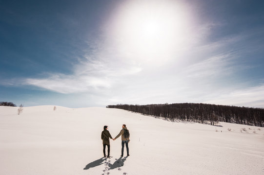 Couple in love walks in winter in the snow. Man and woman traveling. Couple in love in the mountains. Travelers in the mountains. Winter walk. Winter adventures. Winter walk