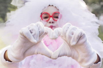 Girl in carnival costume makes heart from fingers