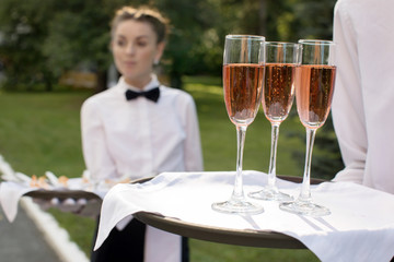 Crop waiter holding tray with glasses on event