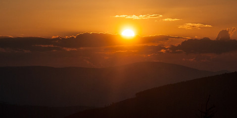 sunset with colorful sky, sun, clouds and hills