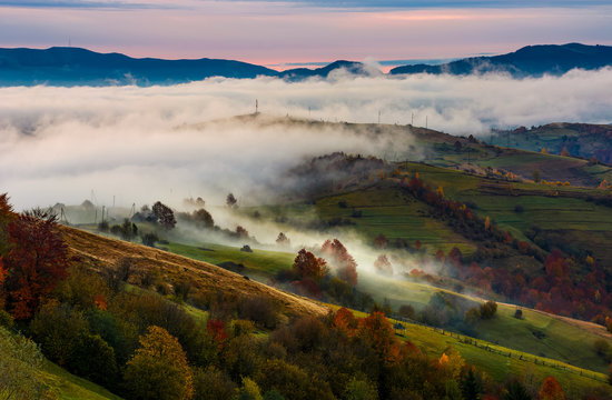 rising fog covers rural fields in mountains