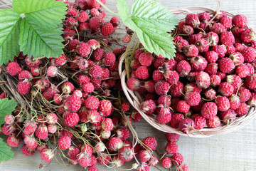 Fresh raw ripe strawberries with green leaves on an old rustic wooden table .