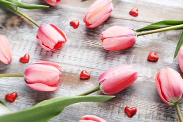 Pink tulips with red hearts on grey wooden table