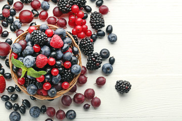 Ripe and sweet berries in basket on white wooden table