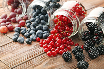 Ripe and sweet berries in bottles on wooden table