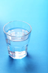 Glass with water on blue background