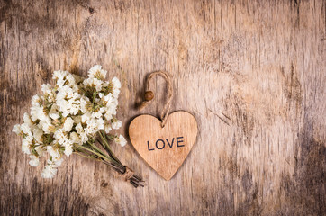 Wooden heart and white flowers on an old wooden board. Backgrounds and textures. St. Valentine's Day.