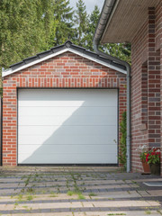Gemauerte Garage mit einen weißen Tor