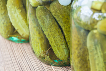 Canned pickled cucumbers in jars on a wooden background. Homemade food. Close-up, selective, focus