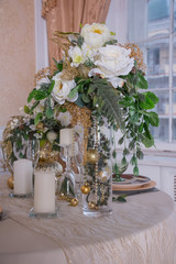 A table prepared for christmas party with  transparent glasses in white and gold colors. Christmas light. celebration table in restaurant or cafe with christmas decoration. magic garlands and candles.