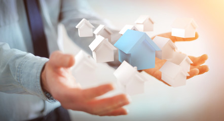 Businessman using 3D rendered small white and blue houses