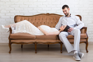 young beautiful pregnant couple on vintage sofa