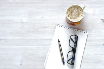 Office desktop with coffee, glasses,  phone, pen