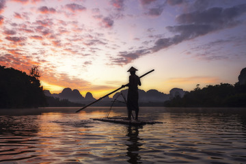 fisherman with his raft is fishing in Nong Thale, a little swamp in Krabi under the sunrise, Thailand.