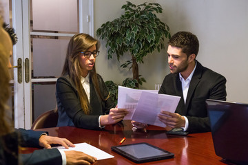 Young people coworking on papers with statistics while sitting at table in office. 