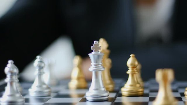Close up shot hand of business woman moving golden chess to defeat a silver king chess on white and black chess board for business challenge competition winner and loser concept
