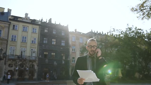 the boy speaks on hte phone and walks around the city