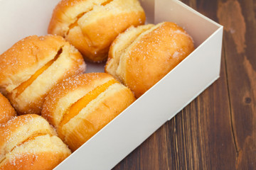 doughnuts with egg cream in white paper box on wooden background