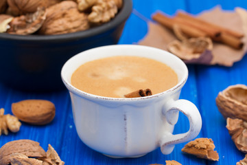a cup of coffee and nuts on wooden background
