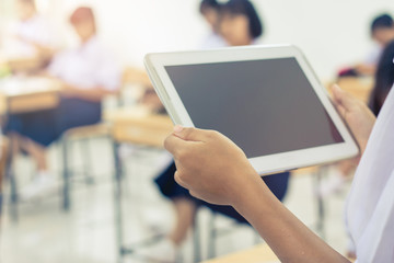 blurred of student testing in exercise, exams answer on a tablet computer in elementary, high school lesson in class room for test exams online education by finger clicking