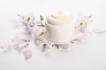 Cute flowers and petals and a jar of natural body cream isolated on white background