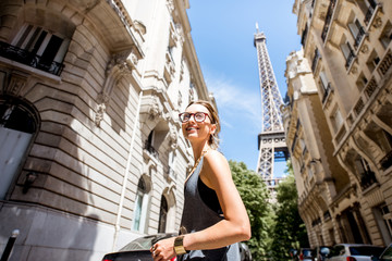 Fototapeta premium Lifestyle portrait of a young stylish woman walking the street with eiffel tower on the background in Paris
