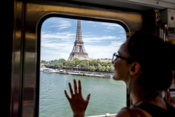 Young woman looking on the Eiffel tower through the train window in Paris. Woman is out of focus