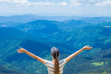 Young woman on the peak of the mountain raise up hand and enjoy beautiful view of sky and mountains. Success concept. Freedom concept