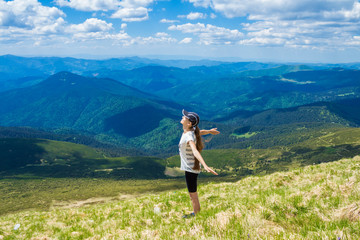 Naklejka premium Young woman on the peak of the mountain raise up hand and enjoy beautiful view of sky and mountains. Success concept. Freedom concept