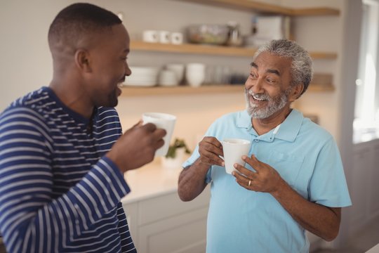 Smiling father and son interacting while having cup of coffee