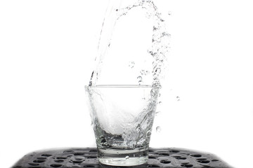 Pour water fresh into glass against the nature in shape water splash isolated on white background .