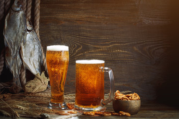 Glasses of beer and dried fish on a wooden table.