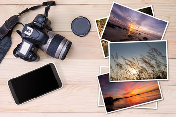 Old camera, smartphone and stack of photos on wooden background