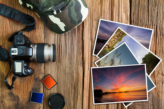 Old camera, cap, memory cards  and stack of photos on vintage wooden background, photography hobby lifestyle concept