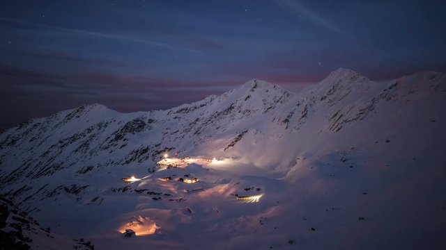 Balea Lake in winter seen from above during night. 	Nightfall over Balea Lake. Snow and ice everywhere around. 4k timelapse.  