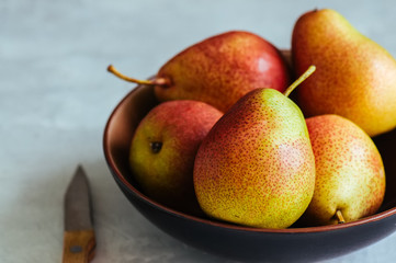 Ripe pears in a plate on a white stone background. Toned.