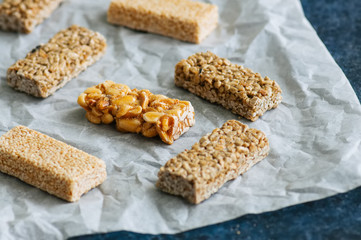 Snacks  - mix of energy bars with peanut, sesame and sunflower seeds on a blue stone background