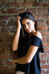 Young beautiful happy woman in casual clothes against brick wall
