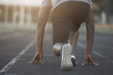 A black man is in starting position before sprinting