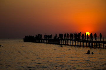 Naklejka na ściany i meble Silhouettes of people on the pier