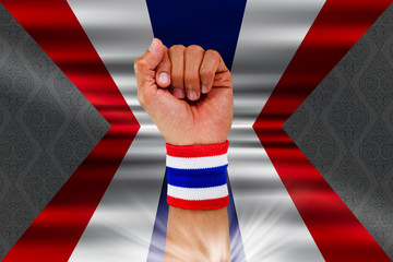 Fototapeta na wymiar Thai national color cloth wristband on the guy's wrist on waving national Thai's flag on vintage Thai pattern background
