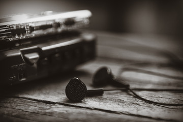 Vintage walkman cassette player with earbuds and tape cassette, retro style toned image