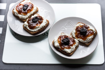 Breakfast with dark bread with white cheese and jam and coffee.  